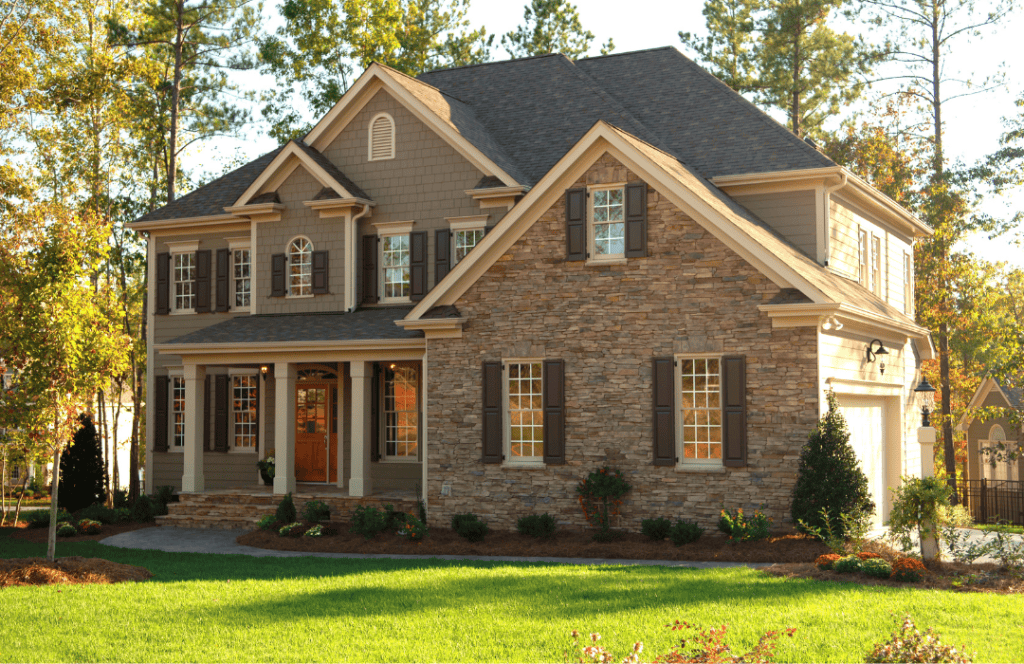 A Kansa City home that features brown brick along with a dark sage green siding.